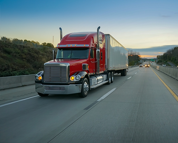 A red semi-trailer truck driving down a highway.