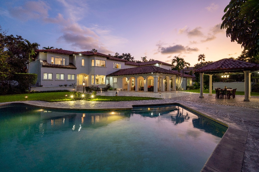 Pool in backyard of a large home at sunset